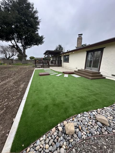 Backyard landscaping with artificial grass, stepping stone walkway and pergola design in Gilroy California