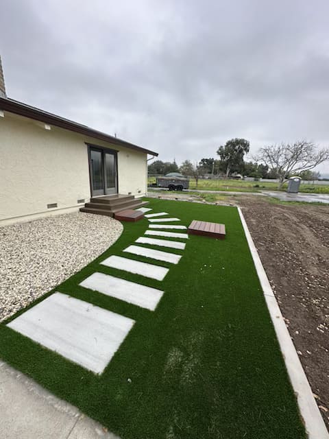 Backyard landscaping with artificial grass, stepping stone walkway and pergola design in Gilroy California